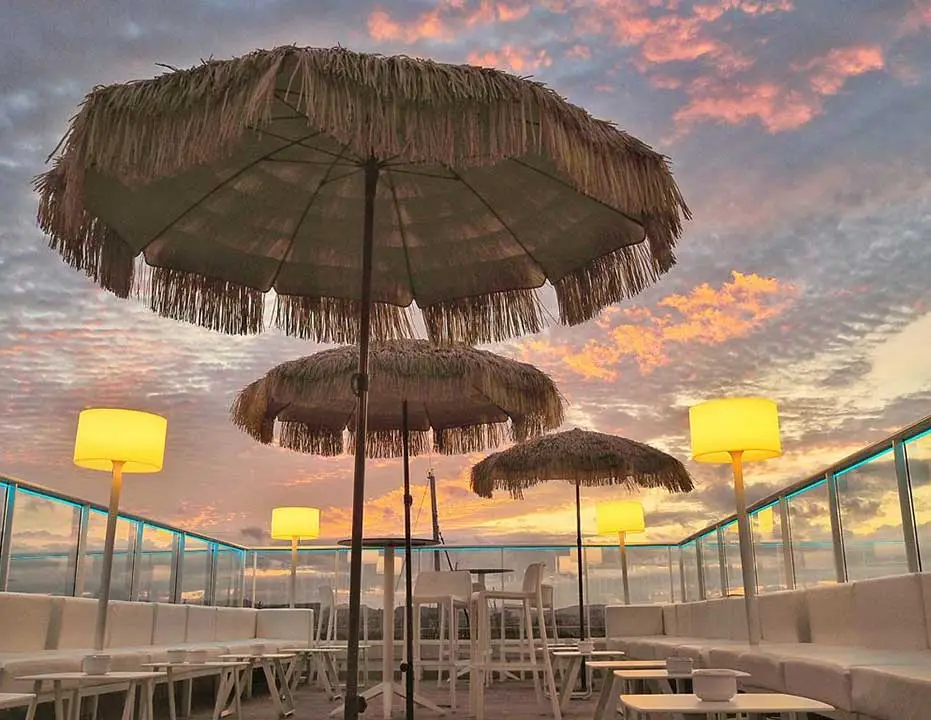 Rooftop lounge with palapa parasols at sunset