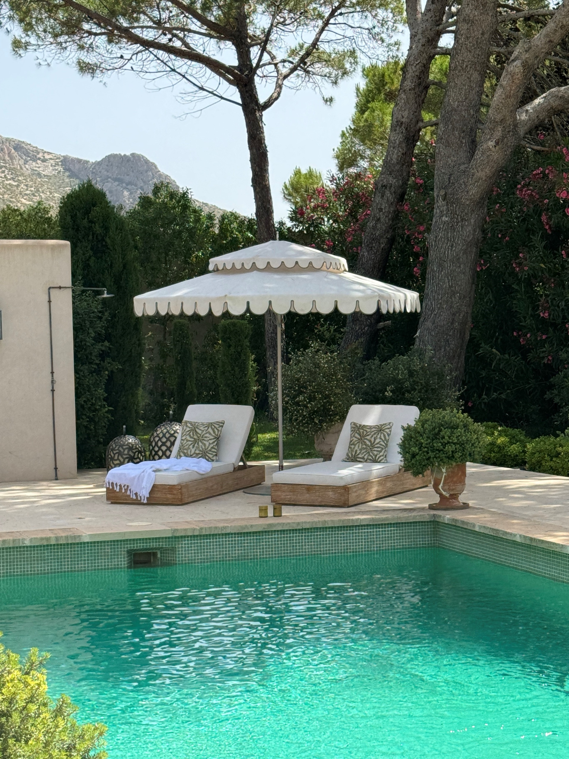 Scalloped parasol shading sun loungers by a private pool