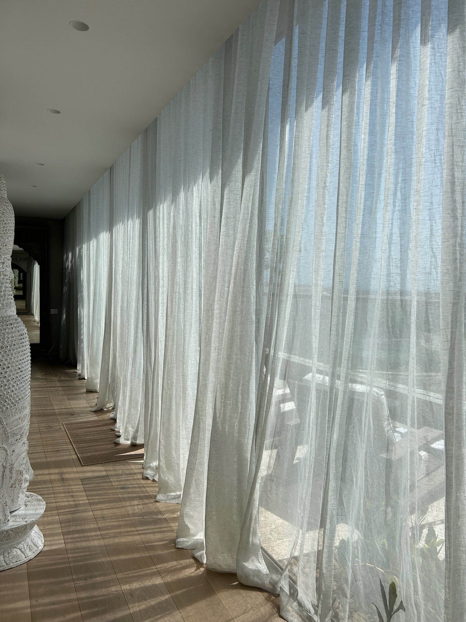 Sheer linen curtains catching the light along a private corridor