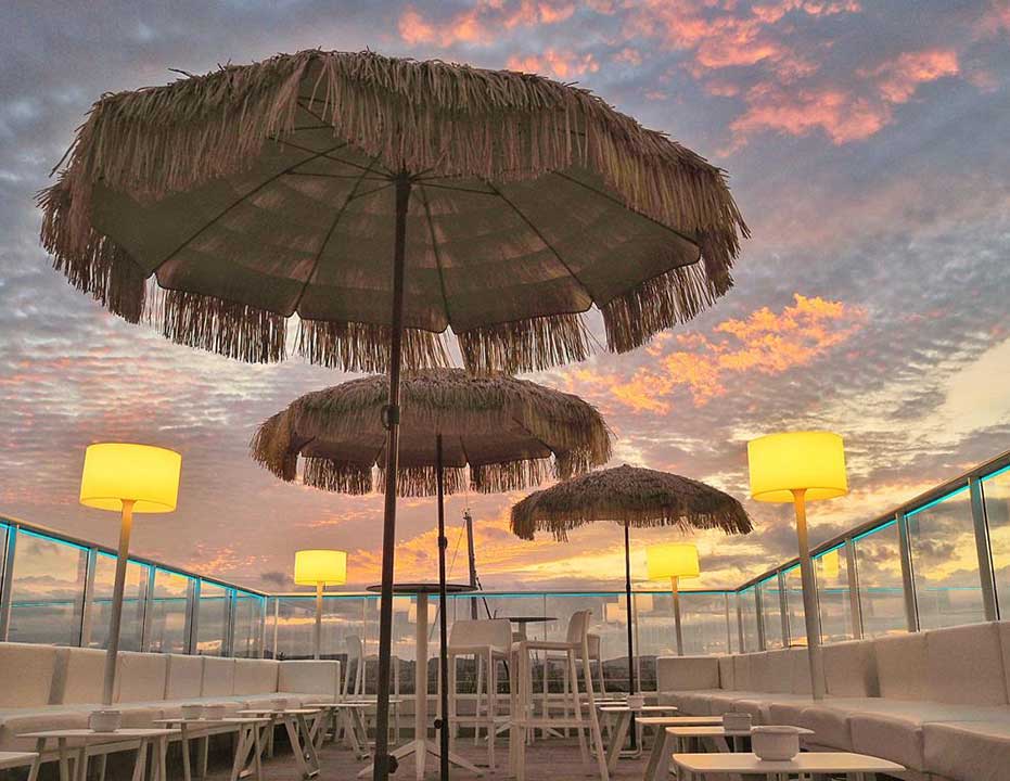 Rooftop lounge with palapa parasols at sunset