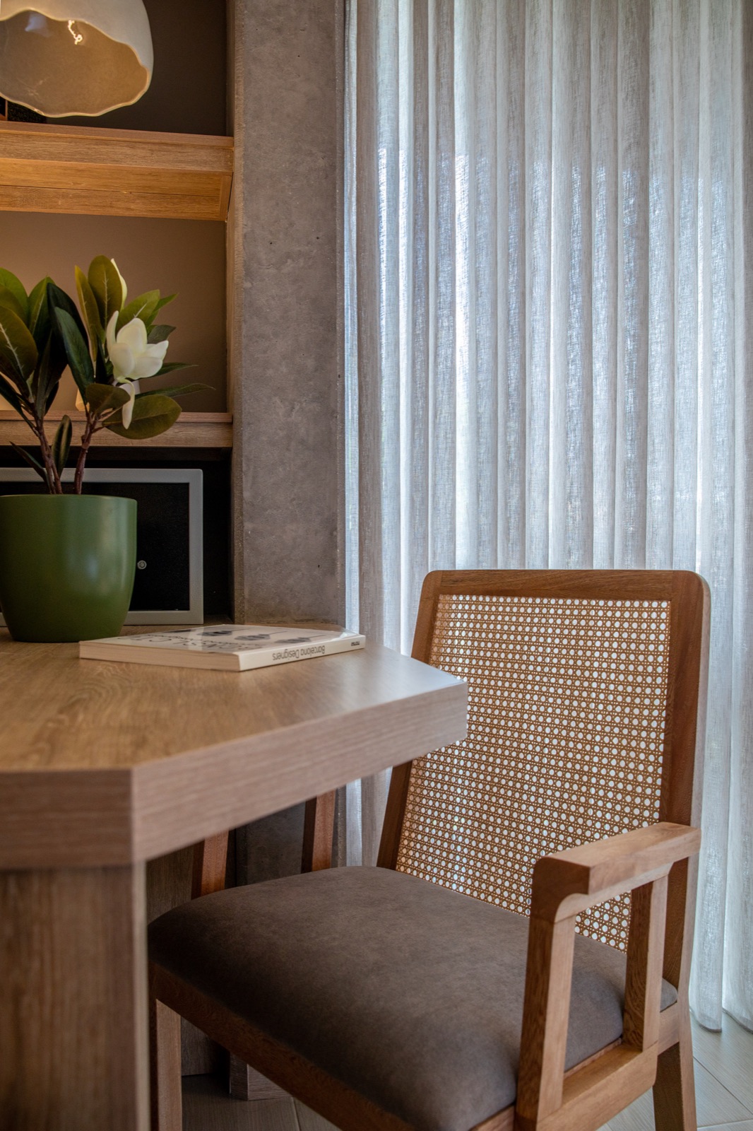 Hotel room desk nook beside sheer drapes